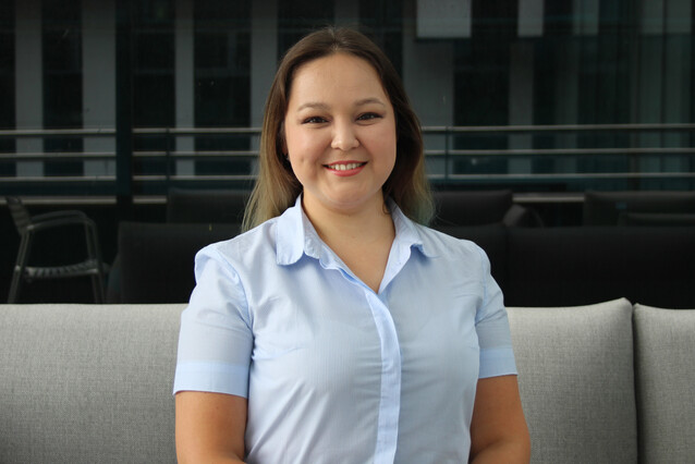 A young woman with long brown hair and a light blue shirt smiles at the camera.