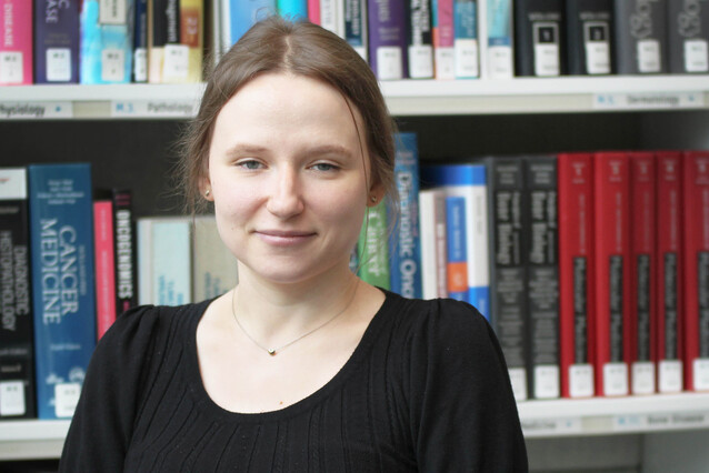 Portrait of white woman standing in front of library, smiling